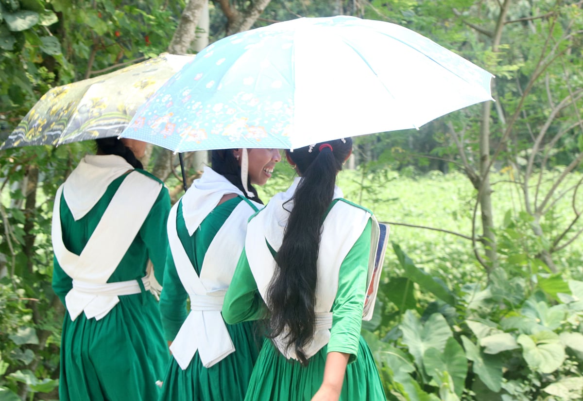প্রখর রোদে ছাতা মাথায় দিয়ে বিদ্যালয়ের পথে তিন শিক্ষার্থী