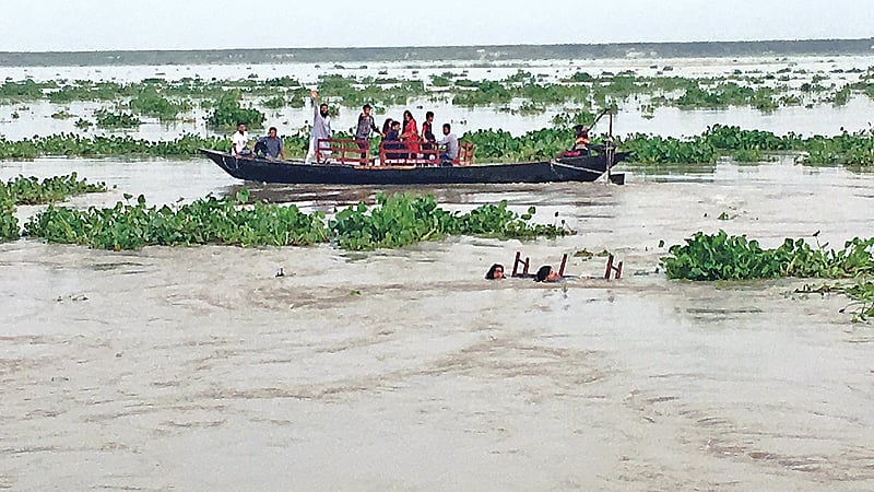 বেঞ্চ ধরে ভেসে রয়েছেন দুই তরুণী। পদ্মা নদীতে রাজশাহী নগরের শ্রীরামপুর এলাকায়।  -PHOTO-14