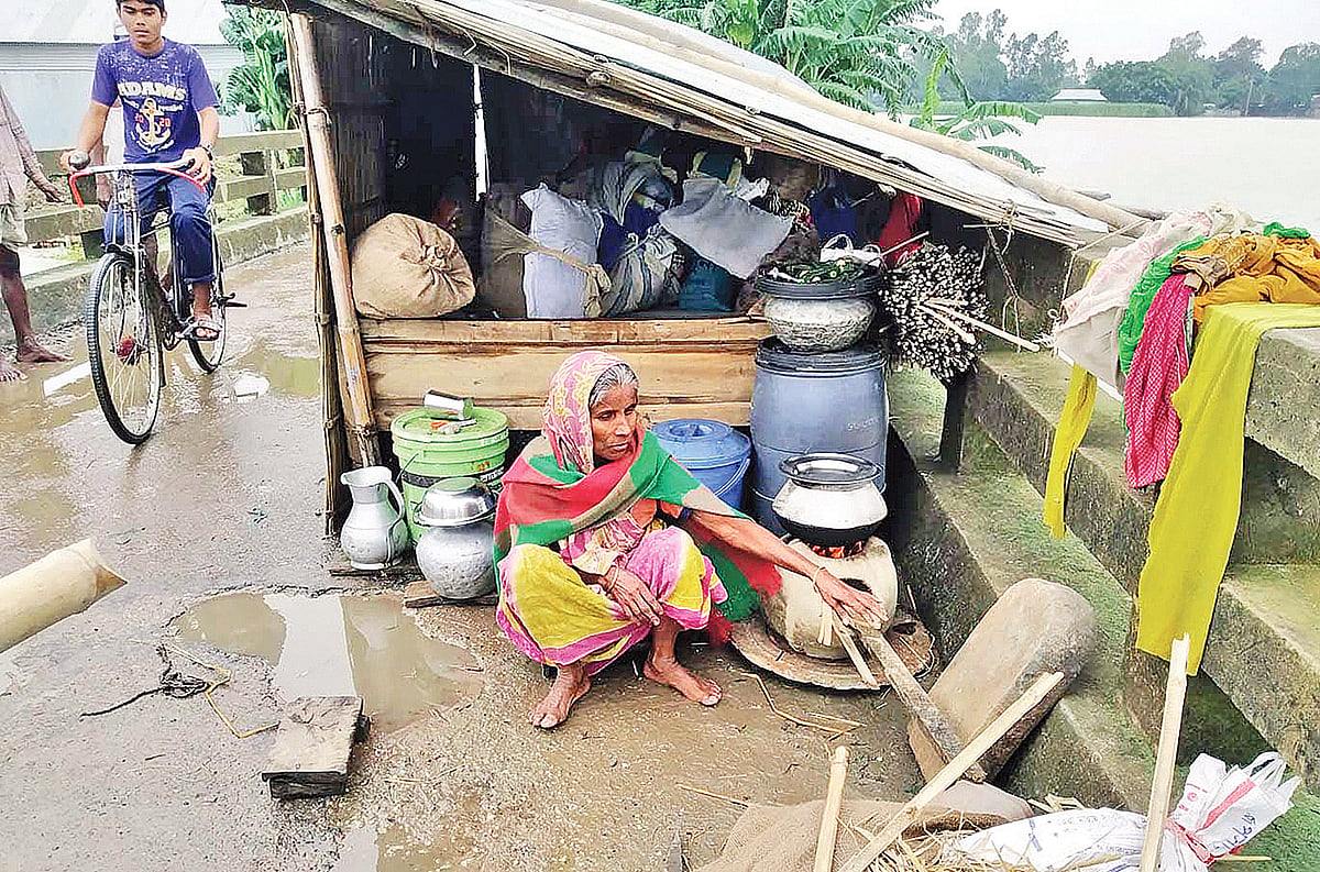 বন্যায় ঘর ভাসিয়ে নিয়েছে। শেষ সম্বলটুকু নিয়ে সেতুর ওপর আশ্রয় নিয়েছেন মনিরা বেগম। গতকাল দুপুরে ইসলামপুর উপজেলার আমতলী সেতুর ওপর। ছবি: প্রথম আলো
