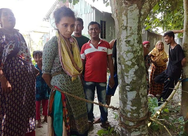 ছেলেধরা সন্দেহে মানসিক ভারসাম্যহীন নারীকে গাছে বেঁধে নির্যাতন করেছেন স্থানীয় লোকজন। পরে পুলিশ গিয়ে তাঁকে উদ্ধার করে। মাদারীপুর, ঢাকা, ২২ জুলাই। ছবি: প্রথম আলো