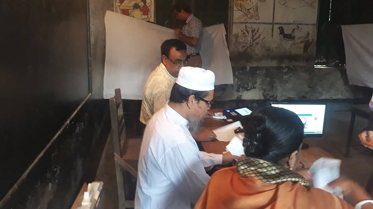 গোপন কক্ষে ভোটার, পাশে দাঁড়িয়ে আশরাফুল আলম চৌধুরী। ছবি: আসাদুজ্জামান।