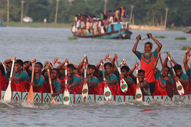 একজন নৌকার মাঝে দাঁড়িয়ে বাদ্য বাজিয়ে সবাইকে উৎসাহ দেন