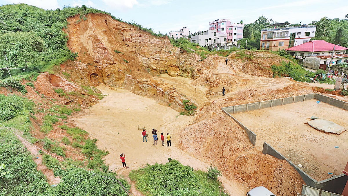 প্রবেশপথে ছিল টিনের বেড়ার একটি ফটক। ফটকের আড়ালে কাটা হয়েছে টিলার এই অংশ। গত শনিবার সিলেট নগরের মজুমদার টিলার ব্রাহ্মণশাসন এলাকায়।  ছবি: প্রথম আলো