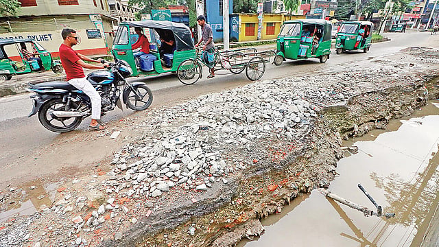 নর্দমার পানির স্রোতে ভেঙে গেছে সড়ক। ভাঙা সড়কে ঝুঁকি নিয়ে চলছে যানবাহন। গতকাল বিকেলে সিলেট সুনামগঞ্জ সড়কের পাঠানটুলা এলাকায়।  ছবি: প্রথম আলো