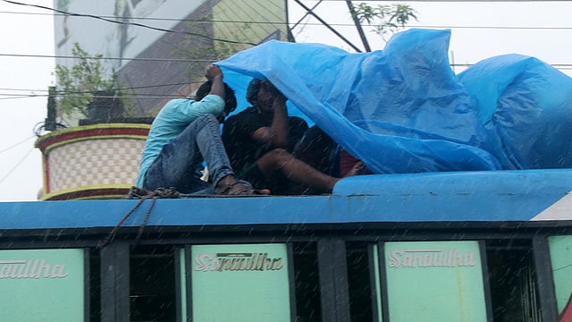 বাসের ছাদে করে ফিরছিলেন। হঠাৎ হানা দিল বৃষ্টি। পলিথিন দিয়ে বৃষ্টি থেকে রক্ষার চেষ্টা।