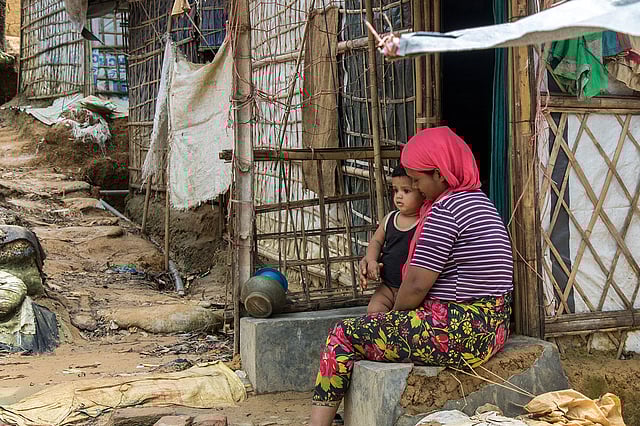 থাকার ঘরের সামনে শিশুকে নিয়ে বসে আছেন রোহিঙ্গা নারী। ছবি: সাবরিনা ইয়াসমীন
