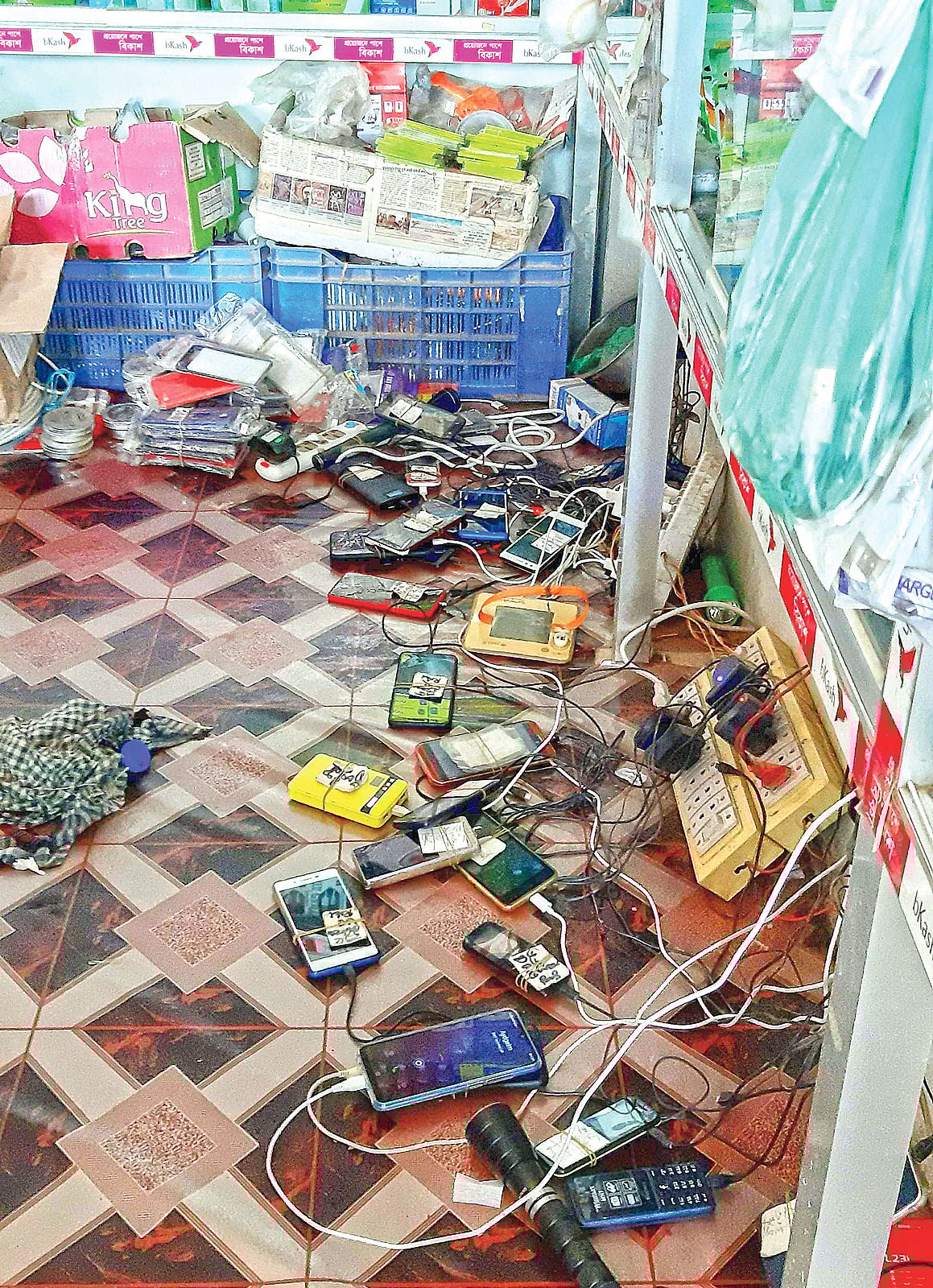 রোহিঙ্গাদের ব্যবহৃত মুঠোফোনে চার্জ দেওয়া হচ্ছে। গতকাল দুপুরে টেকনাফের লেদা রোহিঙ্গা শরণার্থীশিবিরে এক দোকানে। ছবি: প্রথম আলো