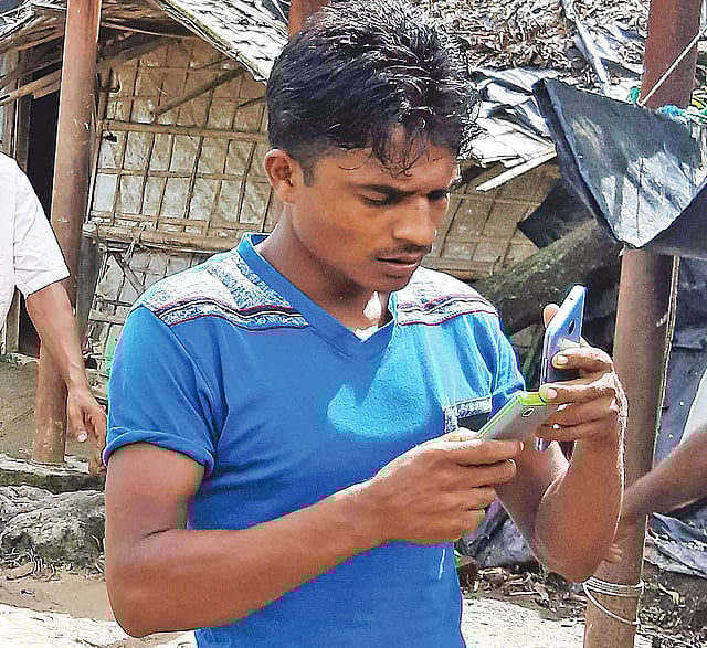 মুঠোফোনে মগ্ন এক রোহিঙ্গা যুবক। গতকাল টেকনাফের লেদা শিবিরে।  প্রথম আলো