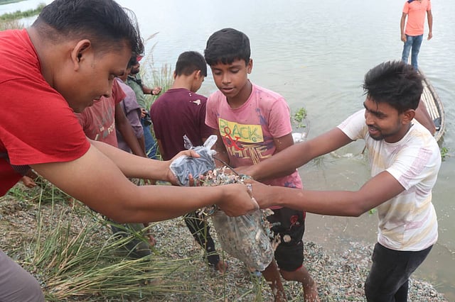 পড়ে থাকা কুচি কুচি ছেঁড়া টাকা ব্যাগে ভরছেন দুজন। শাজাহানপুর, বগুড়া, ২৪ সেপ্টেম্বর। ছবি: সোয়েল রানা