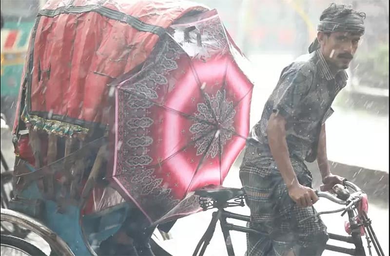 ছাতা দিয়ে বৃষ্টির ছাঁট আড়াল করার চেষ্টা। দোয়েল চত্বর, ঢাকা, ২৩ অক্টোবর। ছবি: আবদুস সালাম