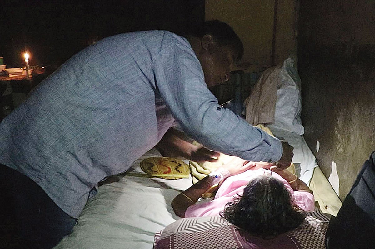 বিদ্যুৎ না থাকায় মুঠোফোনের টর্চ জ্বালিয়ে রোগীদের সেবা দিচ্ছেন চিকিৎসক। গত সোমবার রাতে পাবনা জেনারেল হাসপাতালে। ছবি: প্রথম আলো