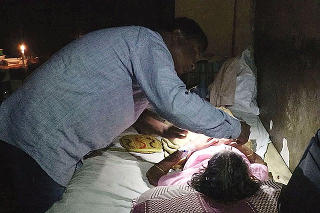 বিদ্যুৎ না থাকায় মুঠোফোনের টর্চ জ্বালিয়ে রোগীদের সেবা দিচ্ছেন চিকিৎসক। গত সোমবার রাতে পাবনা জেনারেল হাসপাতালে। ছবি: প্রথম আলো