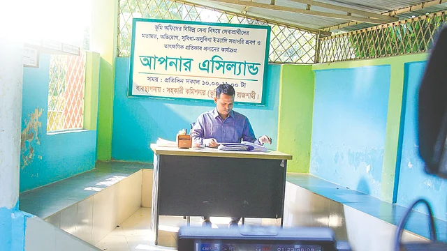 পবা ভূমি অফিসে আসা মানুষদের দ্রুত সেবা দিতেই ‘মাটির মায়া’ নামে এই শেড তৈরি করেছিলেন শাহাদত হোসেন। তথ্যচিত্রের জন্য আবারও সেখানে বসলেন তিনি। ছবি: সংগৃহীত