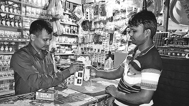 নিজ দোকানে ক্রেতাকে পণ্য দেখাচ্ছেন আমিনুল ইসলাম। সাম্প্রতিক ছবি।  প্রথম আলো