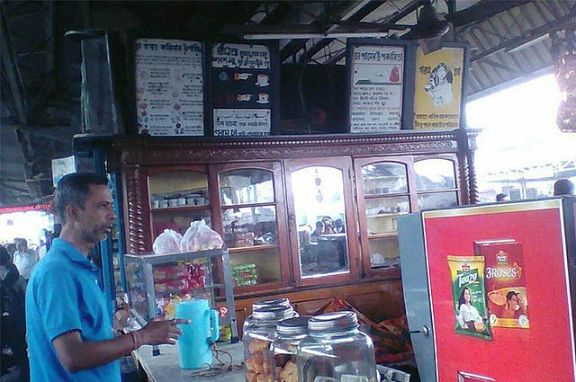 রেলের ইংরেজ আমলের ক্যাটারিং কন্ট্রাক্টর এইচ সি দে, দমদমের এই দোকানটি চালাতেন। তিনি বিনে পয়সায় চা-ও সরবরাহ করতেন রেলযাত্রীদের। তাঁর সময় থেকেই বিজ্ঞাপনগুলো রয়ে গেছে এখানে। দেবদত্ত গুপ্তের ‘দমদম স্টেশনের চা-এর দোকানের ঐতিহাসিক বিজ্ঞাপন’ শীর্ষক লেখা থেকে ছবিটি সংগ্রহ করা।