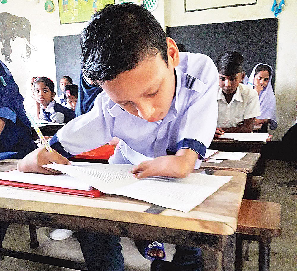 পরীক্ষা দিচ্ছে প্রতিবন্ধী ছাত্র মো. রবিউল। গতকাল বরকোটা সরকারি প্রাথমিক বিদ্যালয় কেন্দ্রে।  ছবি: প্রথম আলো