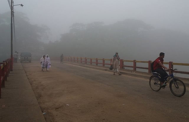 কুয়াশার চাদরে ঢেকে গেছে চারদিক, শীতের সকালে সেতু এলাকা দিয়ে কাজে যাওয়া।