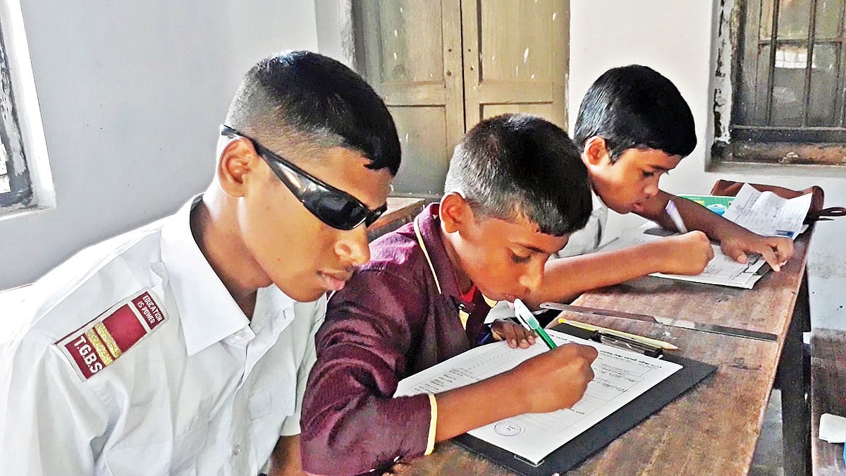 শ্রুতলেখক নিয়ে পরীক্ষা দিচ্ছে মহির উদ্দিন (বাঁয়ে)। ঠাকুরগাঁও বালিকা উচ্চবিদ্যালয়ে।