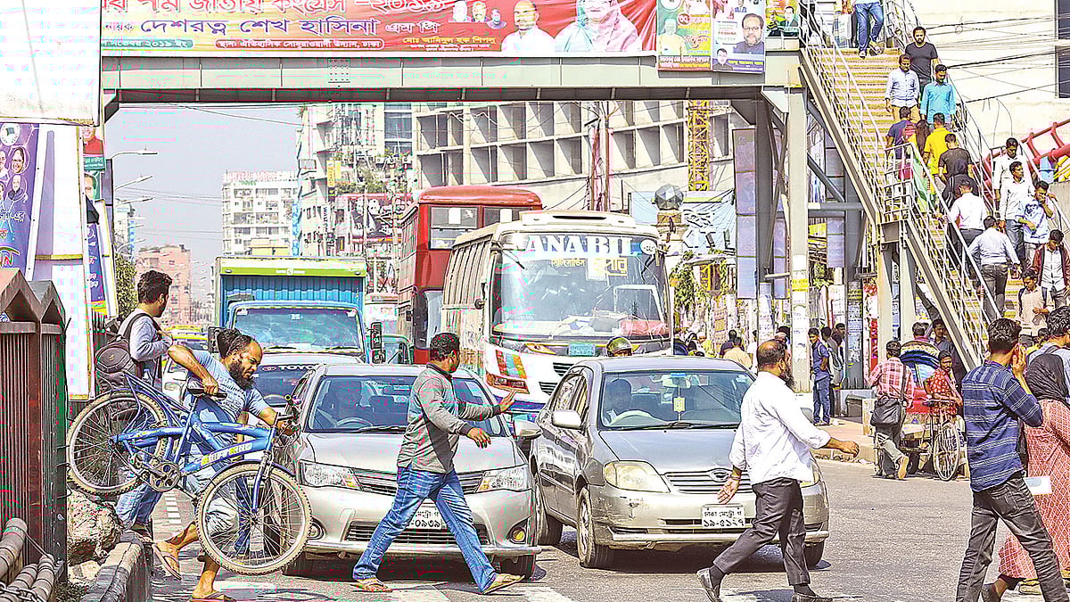 ওপরে আবরার পদচারী–সেতু। তারপরও ঝুঁকি নিয়ে নিচ দিয়ে পারাপার চলছেই। গতকাল যমুনা ফিউচার পার্কের সামনে।  ছবি: প্রথম আলো
