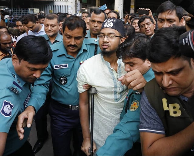 রায় ঘোষণার পর আইএসের প্রতীক সম্বলিত টুপি পরে আদালত কক্ষ থেকে বের হন মৃত্যুদণ্ড পাওয়া জঙ্গি রাকিবুল ইসলাম রিগ্যান ওরফে রাফিউল ইসলাম। ছবি: দীপু মালাকার