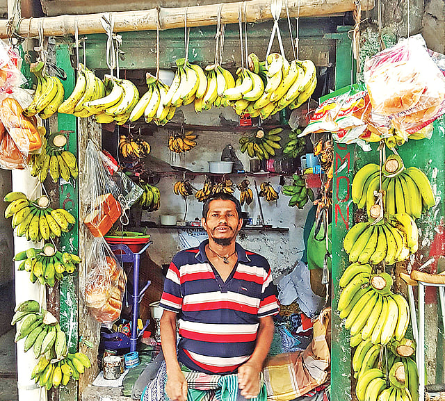কলার দোকানে নান্নু, ৪০ বছর ধরে কলা বিক্রি করছেন িতনি। গত রোববার সকালে।