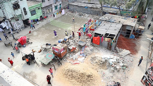 বধ্যভূমির একপাশে গড়ে উঠেছে ঘরবাড়ি, অন্যপাশে ব্যাডমিন্টন খেলার কোর্ট ও ভাগাড়। রাইনখোলা, মিরপুর, ঢাকা, ১৬ ডিসেম্বর। ছবি: আবদুস সালাম