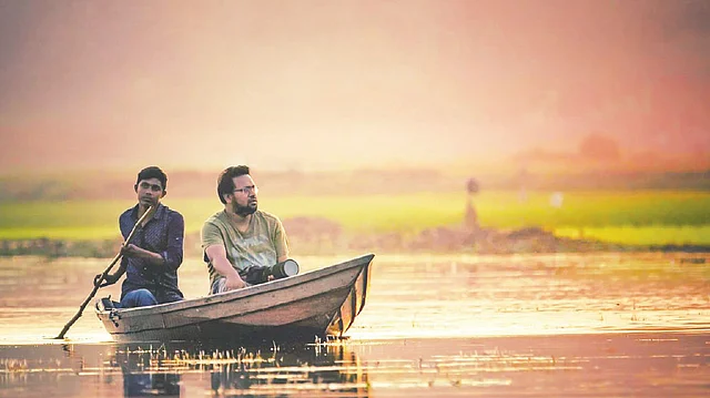 একজন আলোকচিত্রীকে নিয়ে নৌকা চালিয়ে নিয়ে যাচ্ছে অনিক। ছবি: মেজবাউল হাসান