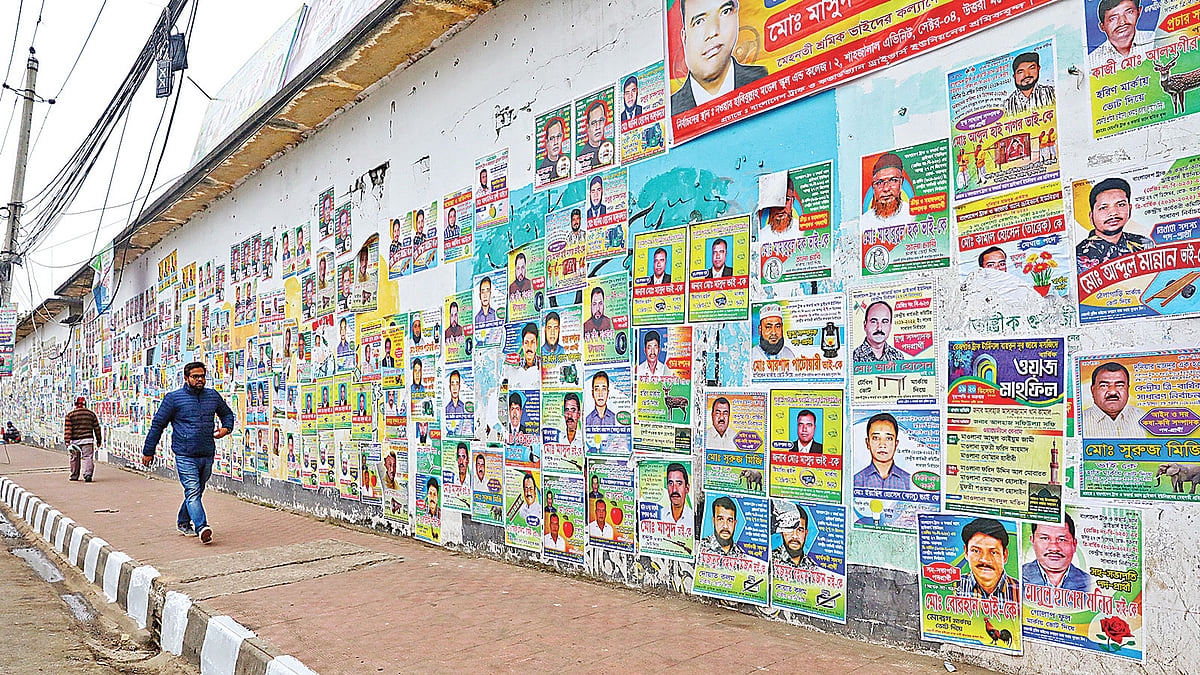 পোস্টারে ঢেকে গেছে দেয়ালচিত্র। গতকাল মেয়র আনিসুল হক সড়কে।  ছবি: প্রথম আলো