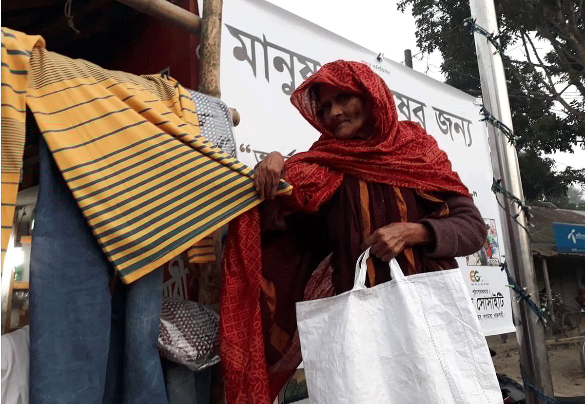 বস্ত্রভান্ডার থেকে শীতের পোশাক নিচ্ছেন এক বৃদ্ধা। ছবি: প্রথম আলো