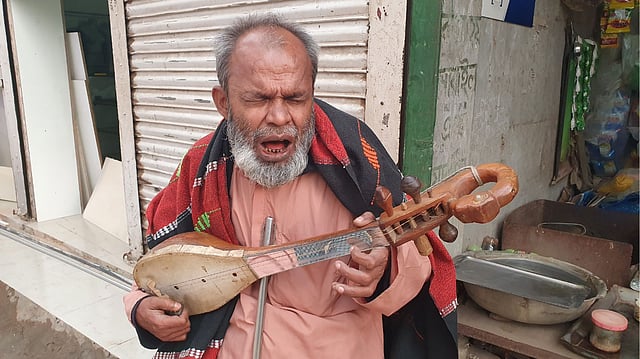 দোতারা বাজিয়ে গান গাইছেন দৃষ্টিপ্রতিবন্ধী মোহন সরকার। এই তিনিই যখন দোতারা রেখে বাঁশি হাতে তুলে নেন, মন্ত্রমুগ্ধ হয়ে যান শ্রোতা-দর্শকেরা। গত সোমবার দুপুরে কালিয়াকৈর উপজেলার সফিপুর বাজারে।  ছবি: প্রথম আলো