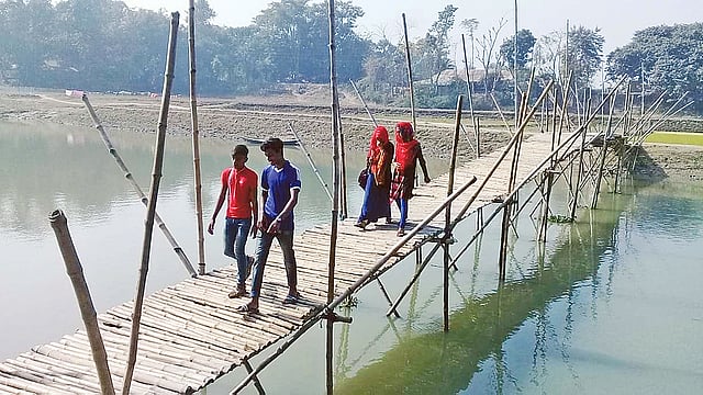 ফকিন্নী নদীর ওপর বাঁশের তৈরি সাঁকো। ভারী মালামাল নিয়ে নদী পার হতে ছয় কিলোমিটার ঘুরতে হয় গ্রামের বাসিন্দাদের। সম্প্রতি রাজশাহীর বাগমারার দহেরঘাটে।  ছবি: প্রথম আলো