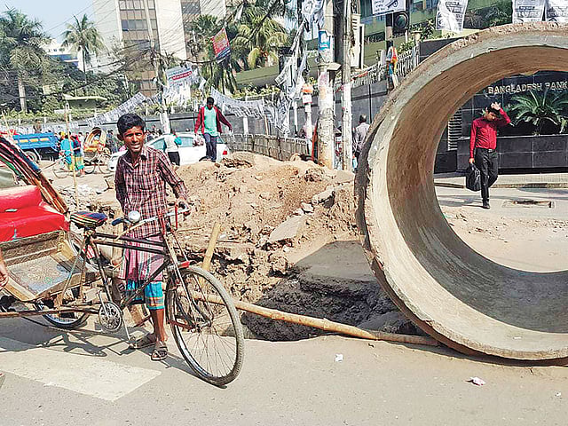 সড়কে গর্ত, পাশে ফেলে রাখা হয়েছে মোটা পাইপ। সম্প্রতি মতিঝিলে বাংলাদেশ ব্যাংকের সামনে।  প্রথম আলো