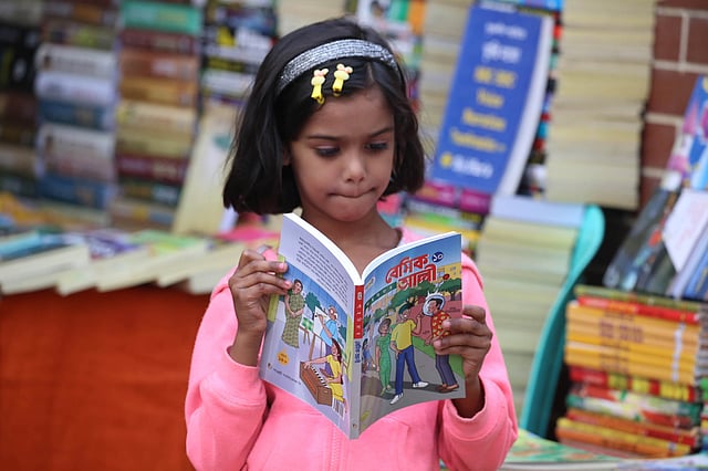 মেলায় বই দেখছে এক খুদে পাঠক।