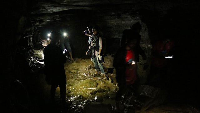 মুঠোফোনের আলো জ্বেলে গুহার ভেতর দিয়ে যাওয়া
