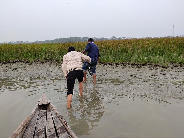 বিশাল চরে কাদার মধ্যে পরিযায়ী পাখির ছবি তোলার জন্য যাচ্ছেন সংবাদকর্মীরা