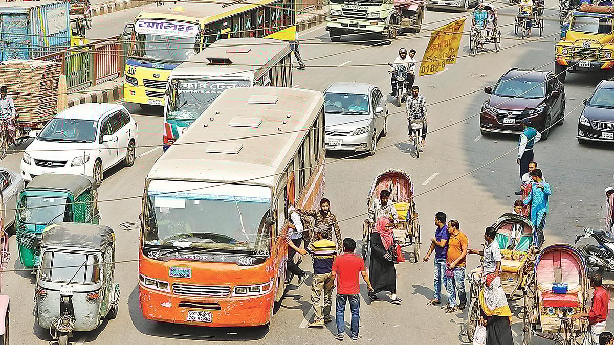 নতুন সড়ক আইন হওয়ার পরও এখনো শৃঙ্খলা ফিরছে না। সড়কের মধ্যেই যাত্রী ওঠানামা করাচ্ছেন বাসচালকেরা। গতকাল দুপুরে রাজধানীর মিরপুর ১ এলাকায়।  ছবি: প্রথম আলো