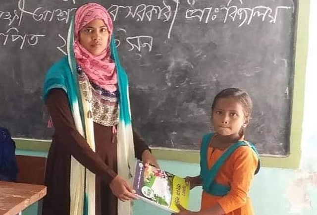 গত মাসে বিদ্যালয়ে নতুন বই উৎসবে এক শিক্ষার্থীর হাতে বই তুলে দিয়েছিলেন তাসলিমা। ছবি: সংগৃহীত