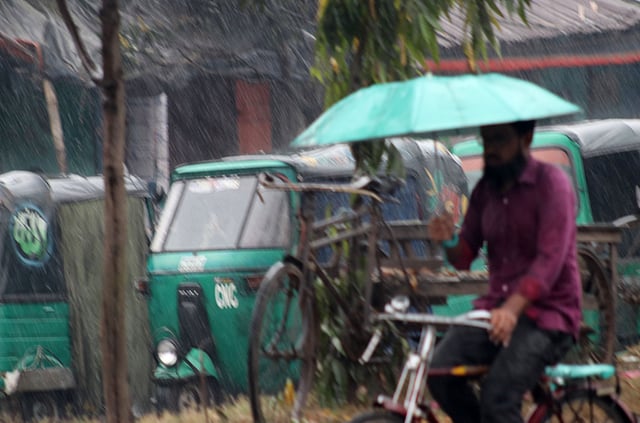 এক হাতে সাইকেল সামলে অন্য হাতে ছাতা মেলে যাত্রা