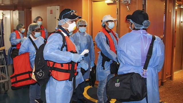 পানামার স্বাস্থ্য মন্ত্রণালয়ের কর্মকর্তারা পানামা সিটির আমাদর বন্দরে পর্যটকদের আগমনের অপেক্ষায় দাঁড়িয়ে আছেন। ছবি: এএফপি