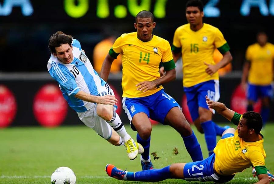 ব্রাজিলের বিপক্ষে কড়া ট্যাকলের শিকার হতেন মেসি। ছবি: এএফপি