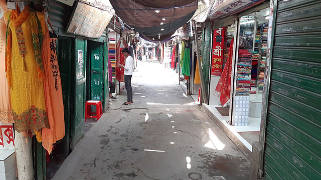 ওষুধ, কাঁচামাল, মুদিদোকান ছাড়া সব ব্যবসাপ্রতিষ্ঠান বন্ধের নির্দেশনা থাকলেও খোলা রয়েছে কিছু কিছু দোকানপাট। তবে মানুষের আনাগোনা হাতে গোনা। আজ শুক্রবার বেলা ১১টায় শিবচর বাজারে। ছবি: প্রথম আলো