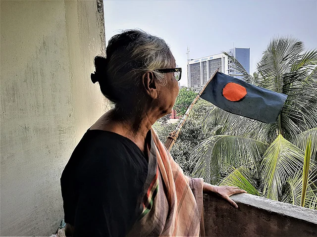 প্রবীণ নিবাসের ব্যালকনিতে জাতীয় পতাকার দিকে তাকিয়ে আছেন চন্দনা শতদ্রু। ছবি: মানসুরা হোসাইন