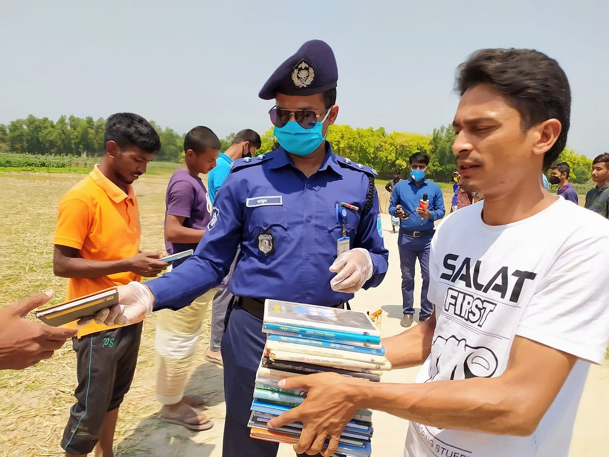 কিশোরদের বই উপহার দিচ্ছেন সহকারী পুলিশ সুপার মো. আল মামুন। চকপাড়া গ্রাম, শ্রীপুর উপজেলা, গাজীপুর, ১ এপ্রিল। ছবি: প্রথম আলো
