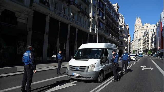 স্পেনের মাদ্রিদের গ্রান ভিয়া স্ট্রিটে একটি গাড়ি থামিয়ে তল্লাশি করছেন মাস্ক পরা পুলিশ কর্মকর্তারা। ছবি: রয়টার্স