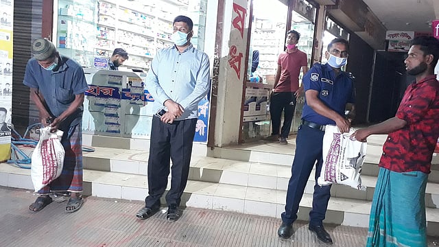 দোকান থেকে খাদ্যসামগ্রী কিনে দুই রিকশা চালককে দিচ্ছেন পুলিশ কর্মকর্তারা। গতকাল শনিবার রাত আটটার দিকে জুড়ী উপজেলার ডাকঘর সড়ক এলাকা থেকে ছবিটি তোলা। ছবি: কল্যাণ প্রসূন