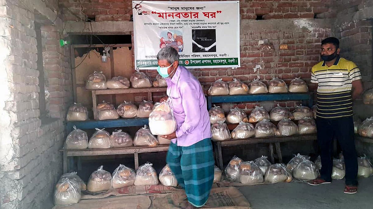 নওগাঁর মহাদেবপুরে ‘মানবতার ঘর’ থেকে খাবার ব্যাগ নিয়ে যাচ্ছেন এক ব্যক্তি। ছবিটি রোববার বিকেলে তোলা। প্রথম আলো