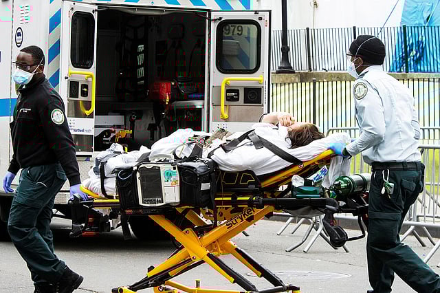 স্বাস্থ্যকর্মীরা একজন অসুস্থ ব্যক্তিকে নিয়ে যাচ্ছেন হাসপাতালে। ছবিটি ৫ এপ্রিল নিউইয়র্ক নগরের এলমহার্স্ট হাসপাতালের সামনে থেকে তোলা। -রয়টার্স