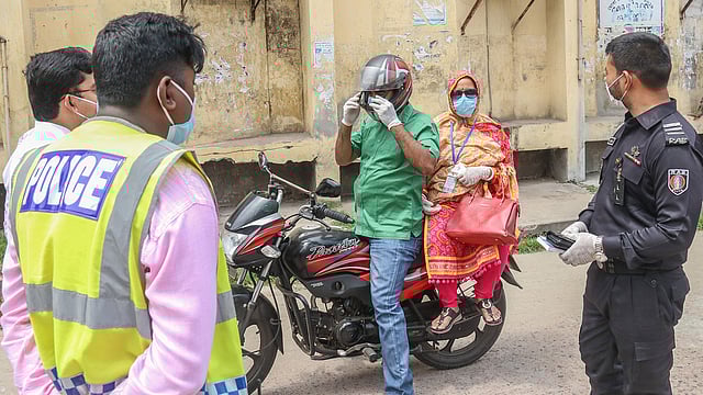 মানুষের অযথা বাইরে ঘোরাফেরা রোধে পুলিশ ও র‌্যাবের সহযোগিতায় কাজ করছেন ভ্রাম্যমাণ আদালত। মোটরসাইকেল চালক ও আরোহীর সঙ্গে কথা বলছেন এক র‌্যাব সদস্য। নিউমার্কেট এলাকা, খুলনা, ১২ এপ্রিল। ছবি: সাদ্দাম হোসেন