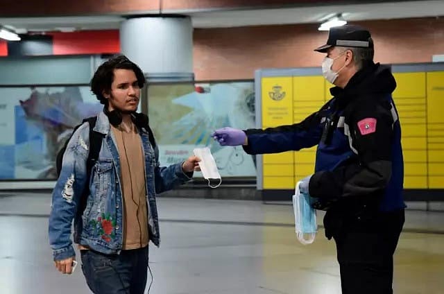 এক পথচারীকে মাস্ক দিচ্ছেন স্পেনের পুলিশ বাহিনীর এক সদস্য। ফাইল ছবি। ছবি: এএফপি