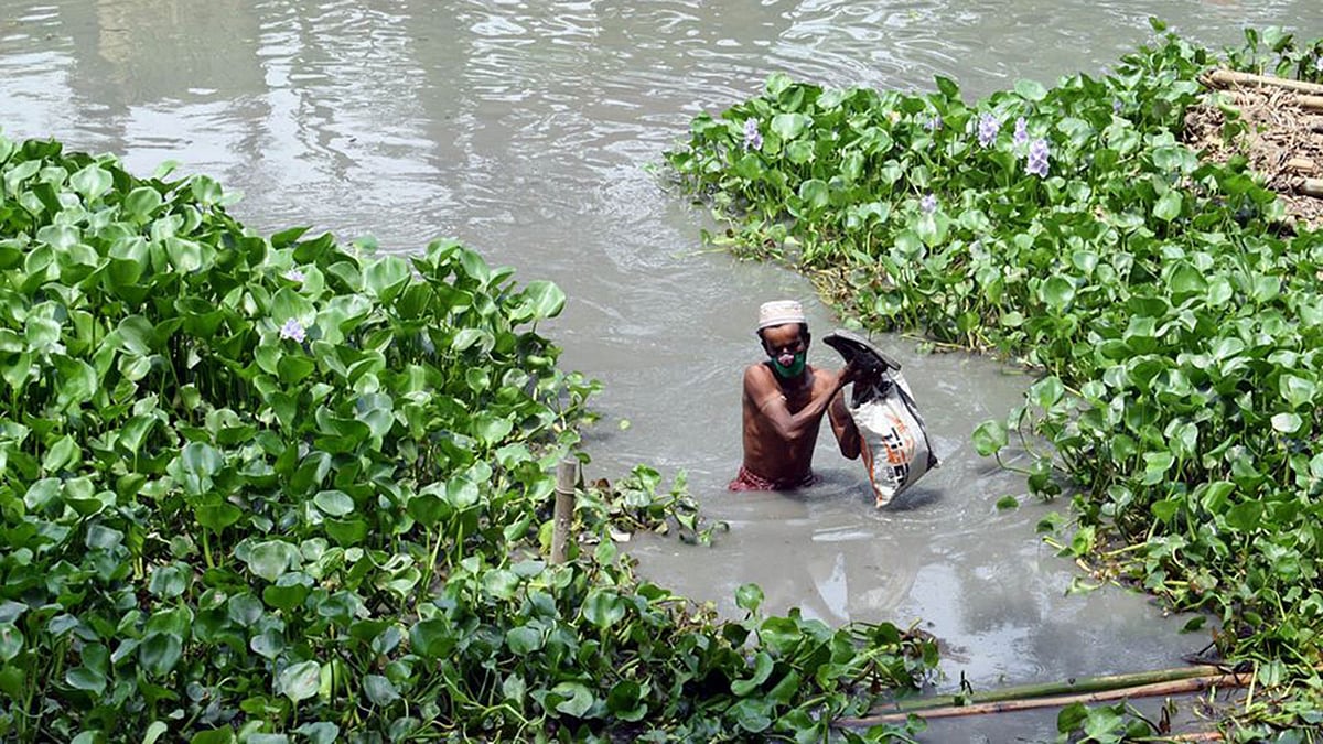 হাতে ব্যাগ নিয়ে খাল পার হচ্ছেন এক ব্যক্তি। বরিশালের গৌরনদী উপজেলার ভুরঘাটা এলাকায়। ছবি: প্রথম আলো